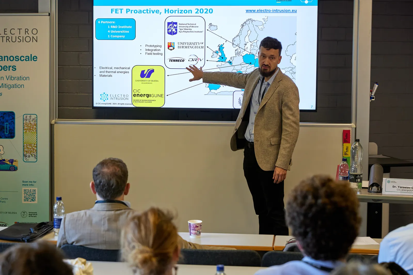 Speaker presenting a project slide to delegates at a research workshop