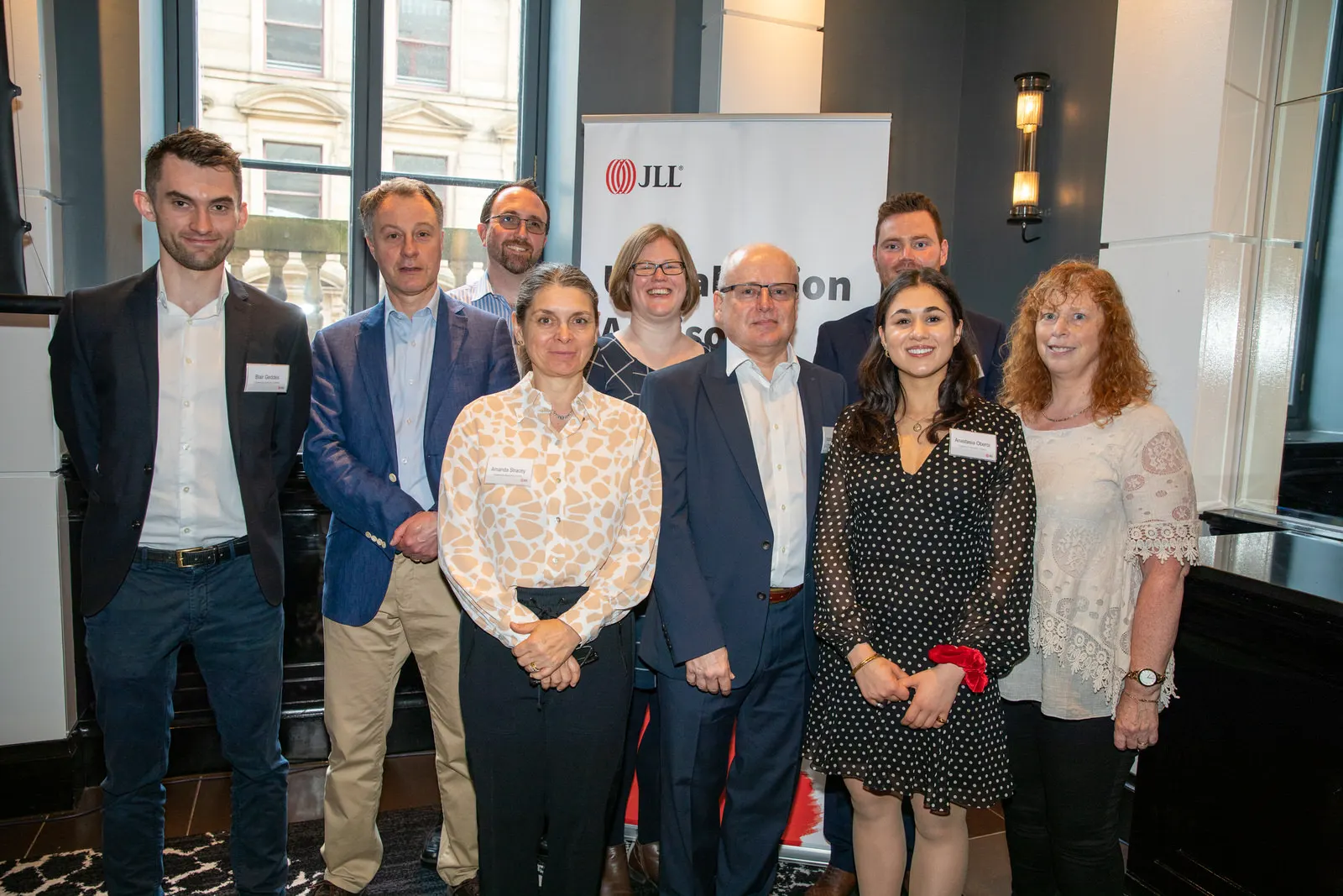 Team group photograph in front of the JLL banner at a corporate conference