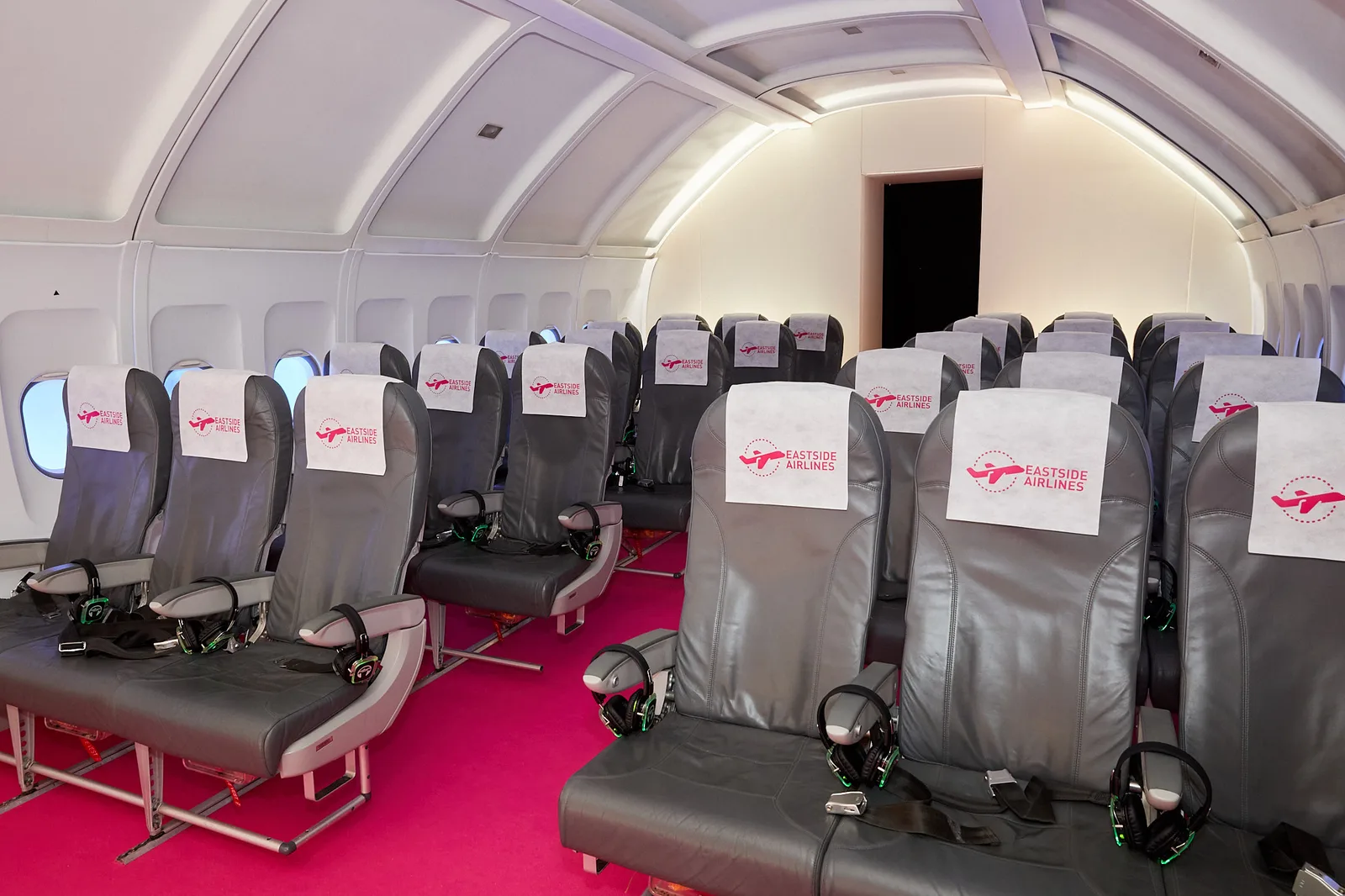 Branded aircraft cabin set piece with printed headrest covers at a corporate event