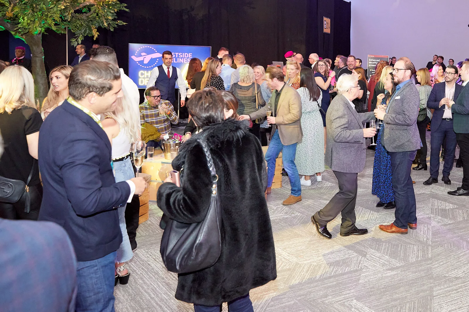 Delegates networking beneath indoor oak trees at a themed conference reception