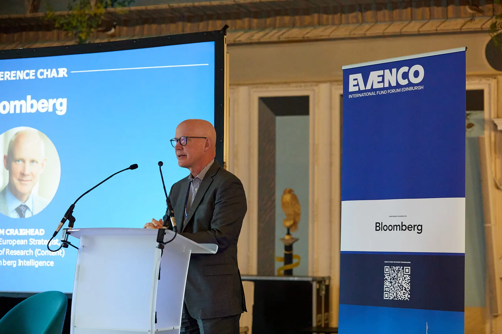 Conference chair speaking at a lectern at a fund forum in Edinburgh