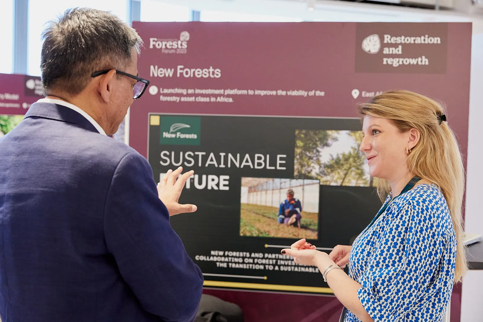 Exhibitor talking a visitor through a display stand at an industry forum