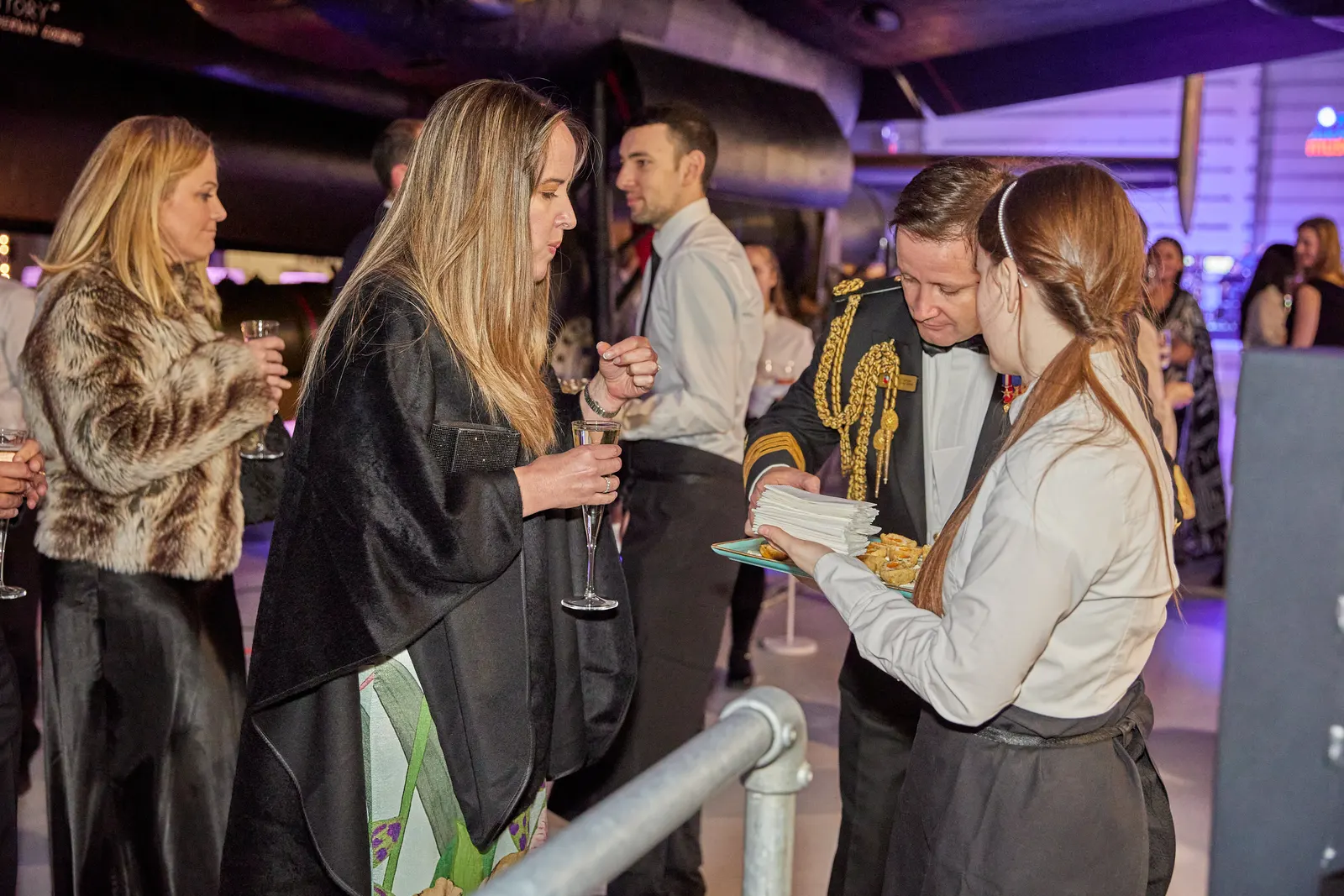 Guests enjoying canapés beneath a historic aircraft at an evening reception