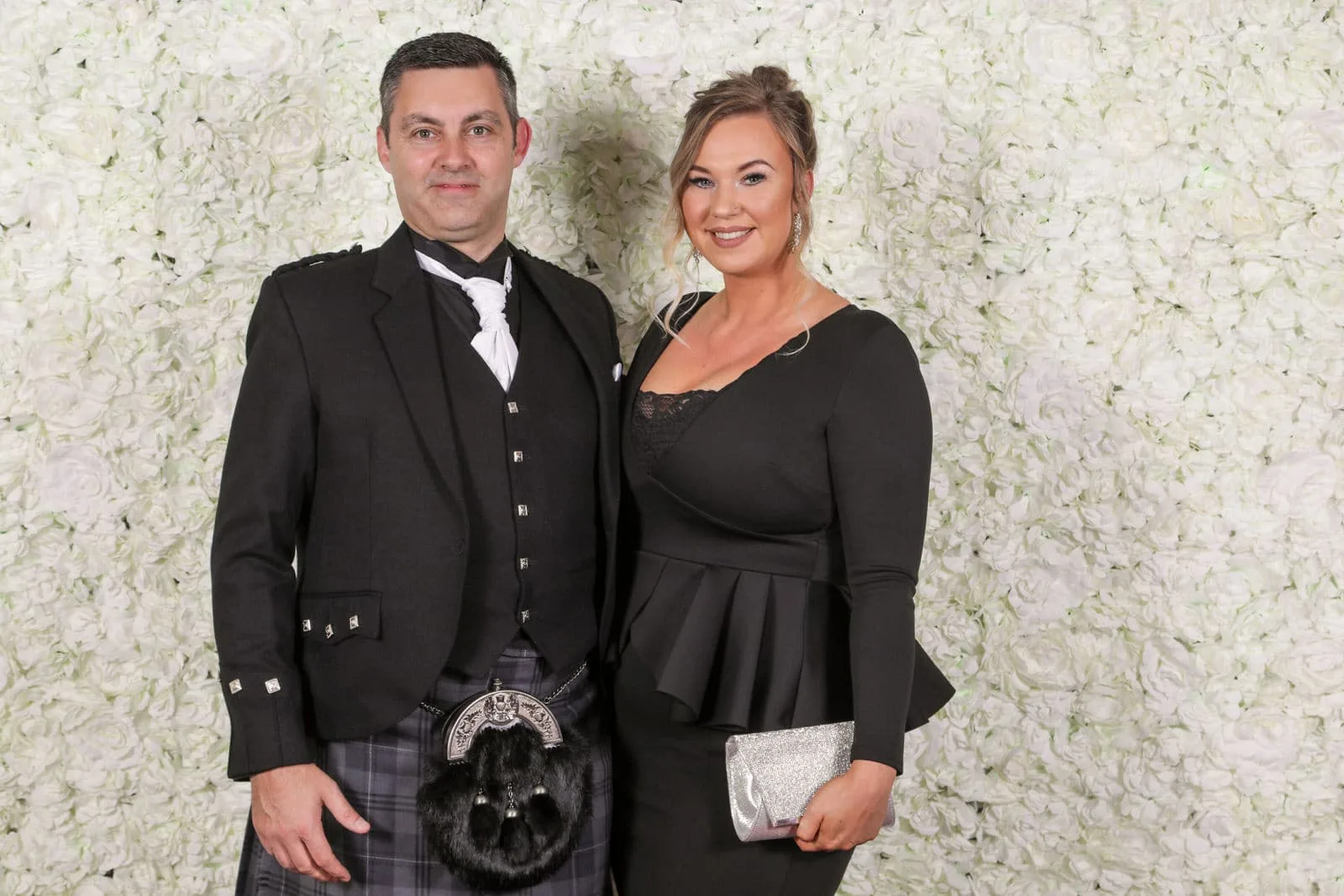 Couple in Highland dress photographed at the pop-up flower-wall studio at a Glasgow event