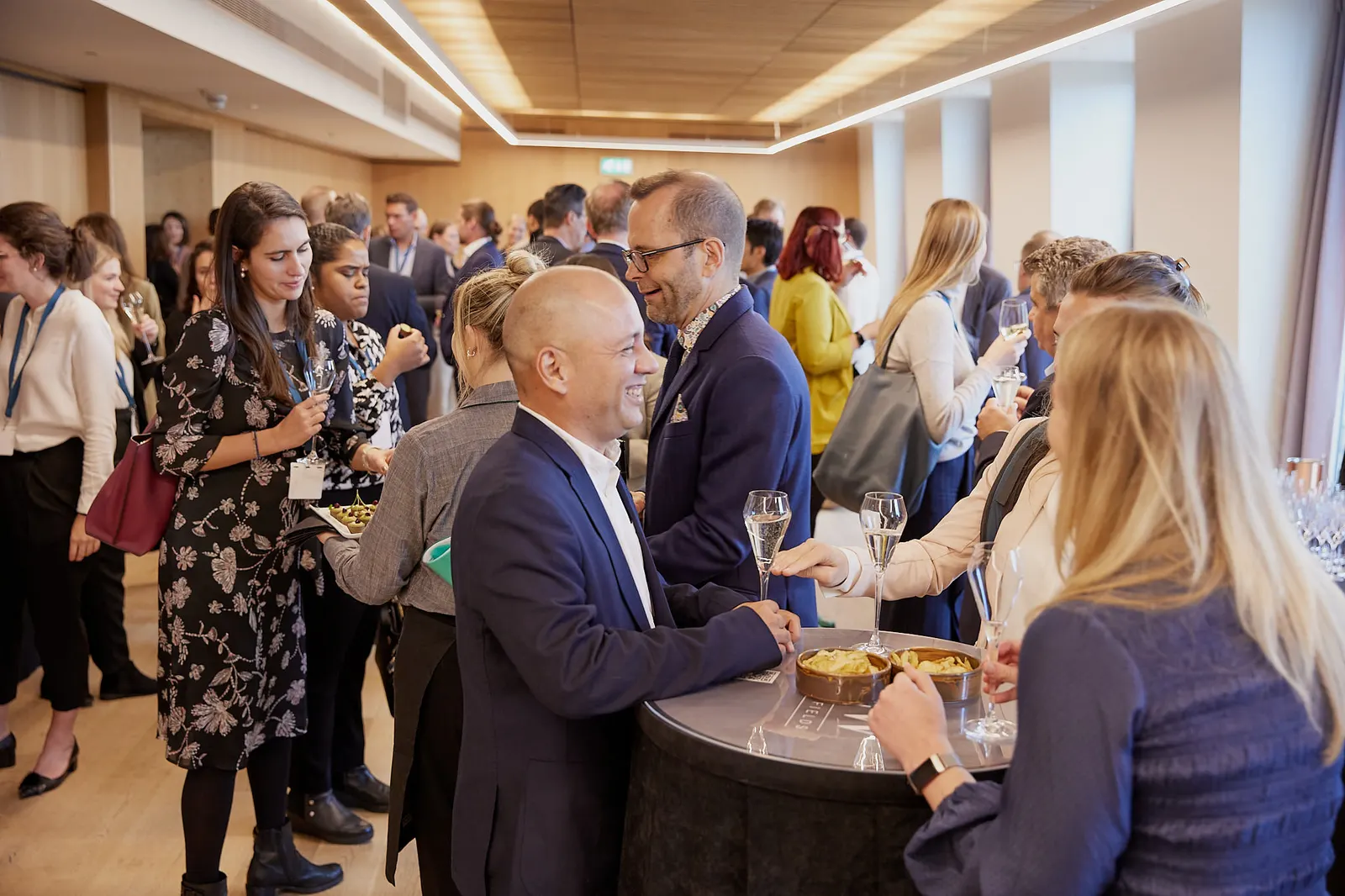 Guests laughing over drinks at a corporate networking reception